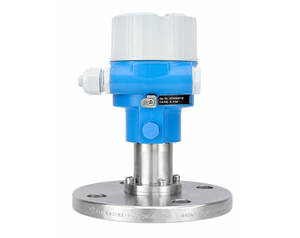 Industrial flow transmitter with blue housing mounted on a stainless steel flange and pipe fittings sticking out the sides.